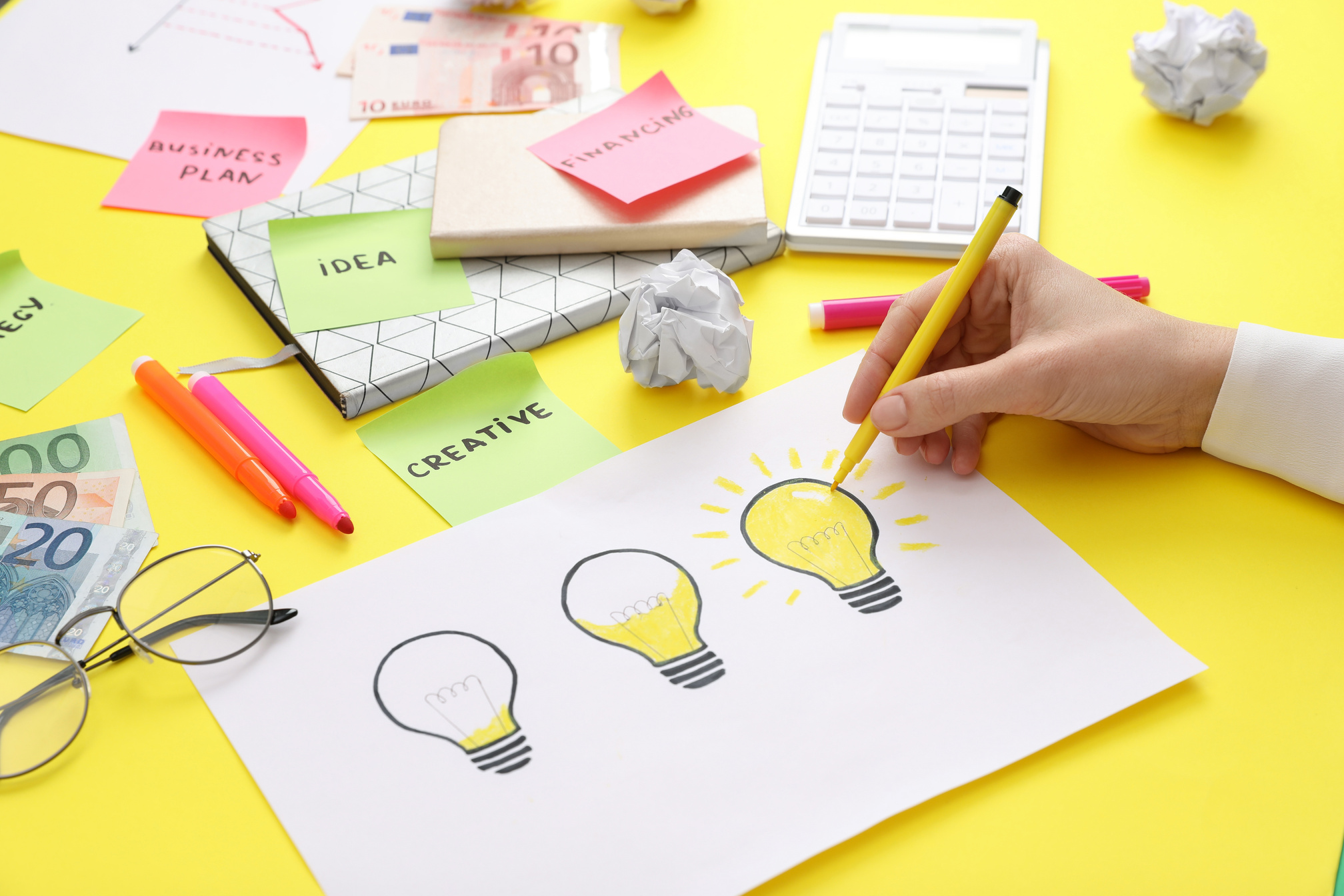 Woman Drawing Lamp on Paper at Yellow Table, Closeup. Startup Co